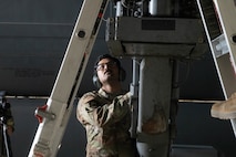 Senior Airman Christo Jose, 23rd Bomber Generation Squadron load team member, observes for safety while his teammates attach an inert GBU-31 to the underside of a B-52H Stratofortress wing at Minot Air Force Base, Oct. 4, 2024. In order to safely load the inert GBU-31 onto the aircraft, two Airmen are needed to attach it to the aircraft while another supervises to ensure safety. (U.S. Air Force photo by Airman 1st Class Wesley Davies)