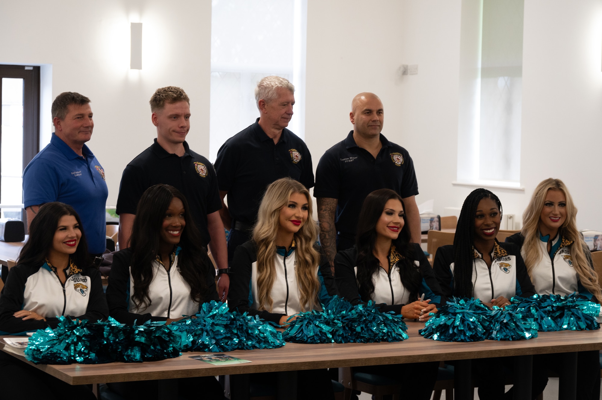Members of the RAF Fairford Fire Department pose with the Jacksonville Jaguars Roar Cheerleader Squad