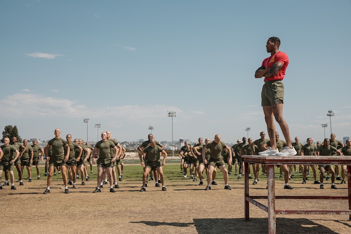 U.S. Marine Corps Staff Sgt. Deandre Lee, a chief drill instructor with Charlie Company, 1st Recruit Training Battalion, guides recruits through dynamic warm-ups prior to a physical training session at Marine Corps Recruit Depot San Diego, California, Oct. 1, 2024. The recruits conducted a series of stations such as side shuffles, ammunition can lifts, planks, single-leg Romanian deadlifts, bicycle crunches, and 440-yard sprints during their physical training event strengthening themselves physically and mentally. (U.S. Marine Corps photo by Cpl. Sarah M. Grawcock)