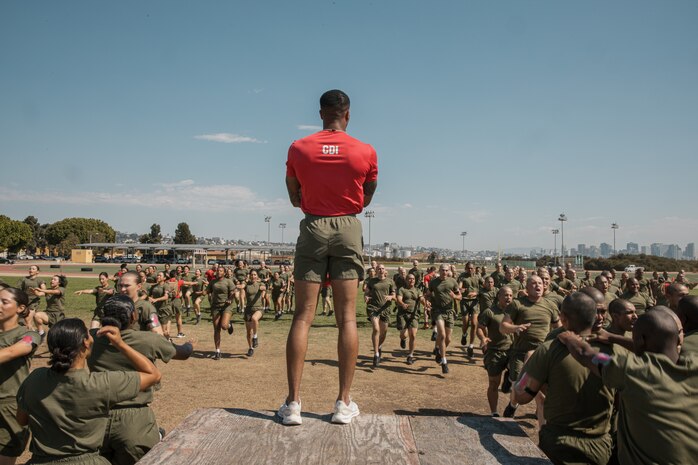 U.S. Marine Corps Staff Sgt. Deandre Lee, a chief drill instructor with Charlie Company, 1st Recruit Training Battalion, guides recruits through dynamic warm-ups prior to a physical training session at Marine Corps Recruit Depot San Diego, California, Oct. 1, 2024. The recruits conducted a series of stations such as side shuffles, ammunition can lifts, planks, single-leg Romanian deadlifts, bicycle crunches, and 440-yard sprints during their physical training event strengthening themselves physically and mentally. (U.S. Marine Corps photo by Cpl. Sarah M. Grawcock)