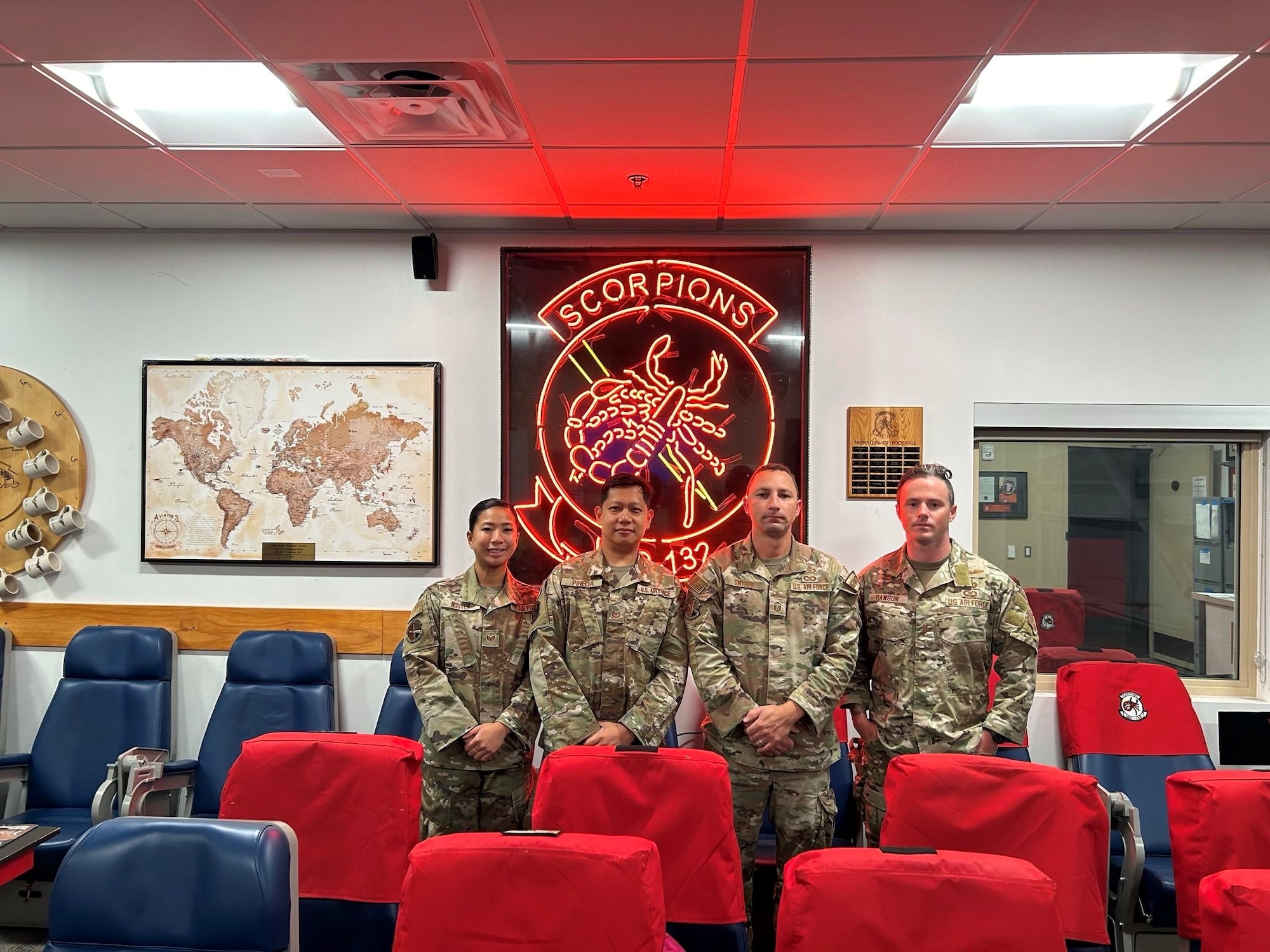 Airmen pose in front of the Navy Electronic Attack Squadron (VAQ-132) EA-18G Growlers sign
