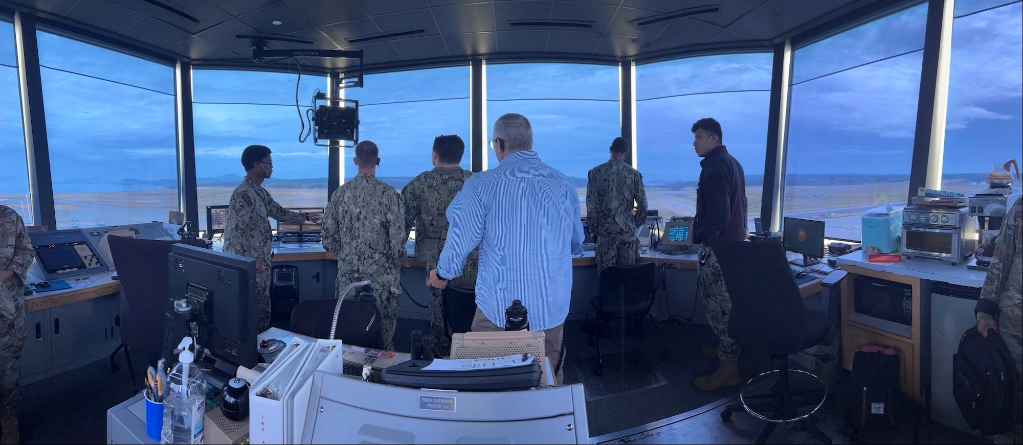 Navy Sailors looking out to the airfield from a control tower