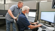 Three omputer technicians sit at computer workstations