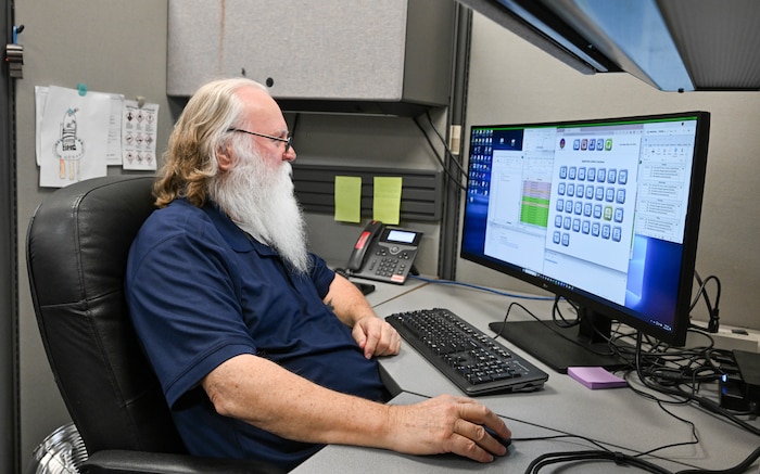 A computer technician sits at a computer workstation