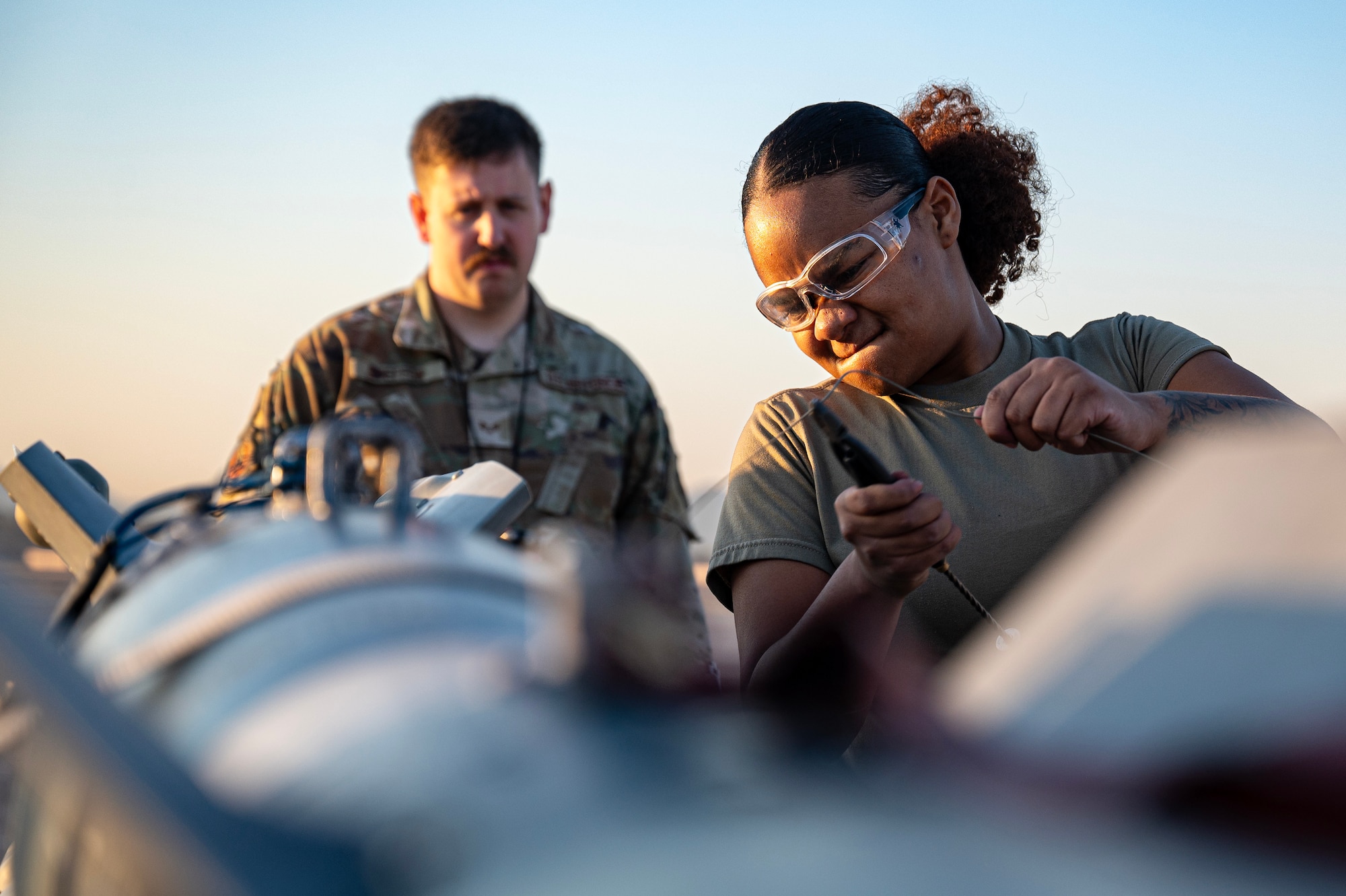 Weapons load crew evaluator evaluates Airman as she prepares an inert bomb during the Quarterly Weapons Load Competition