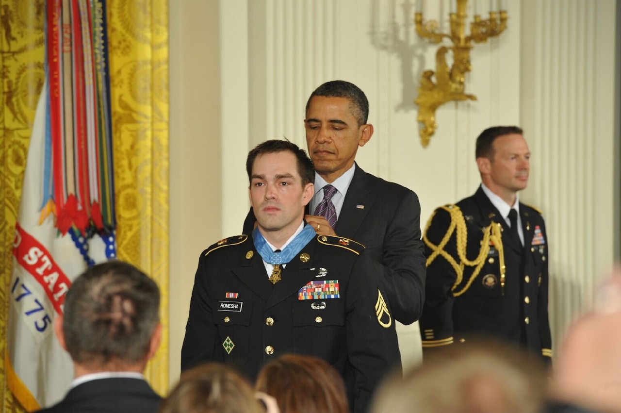 A man places a medal around another man’s neck.