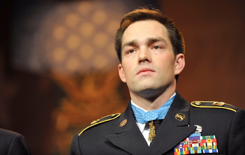 A man wearing a medal around his neck looks forward.