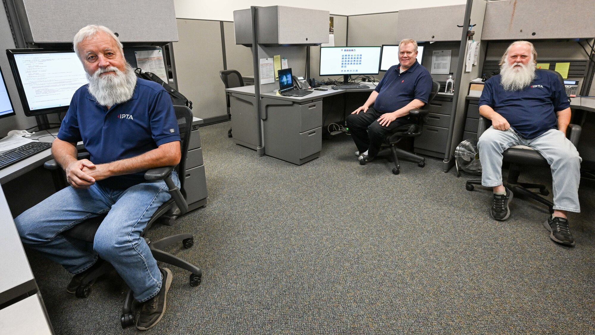 Three omputer technicians sit at computer workstations