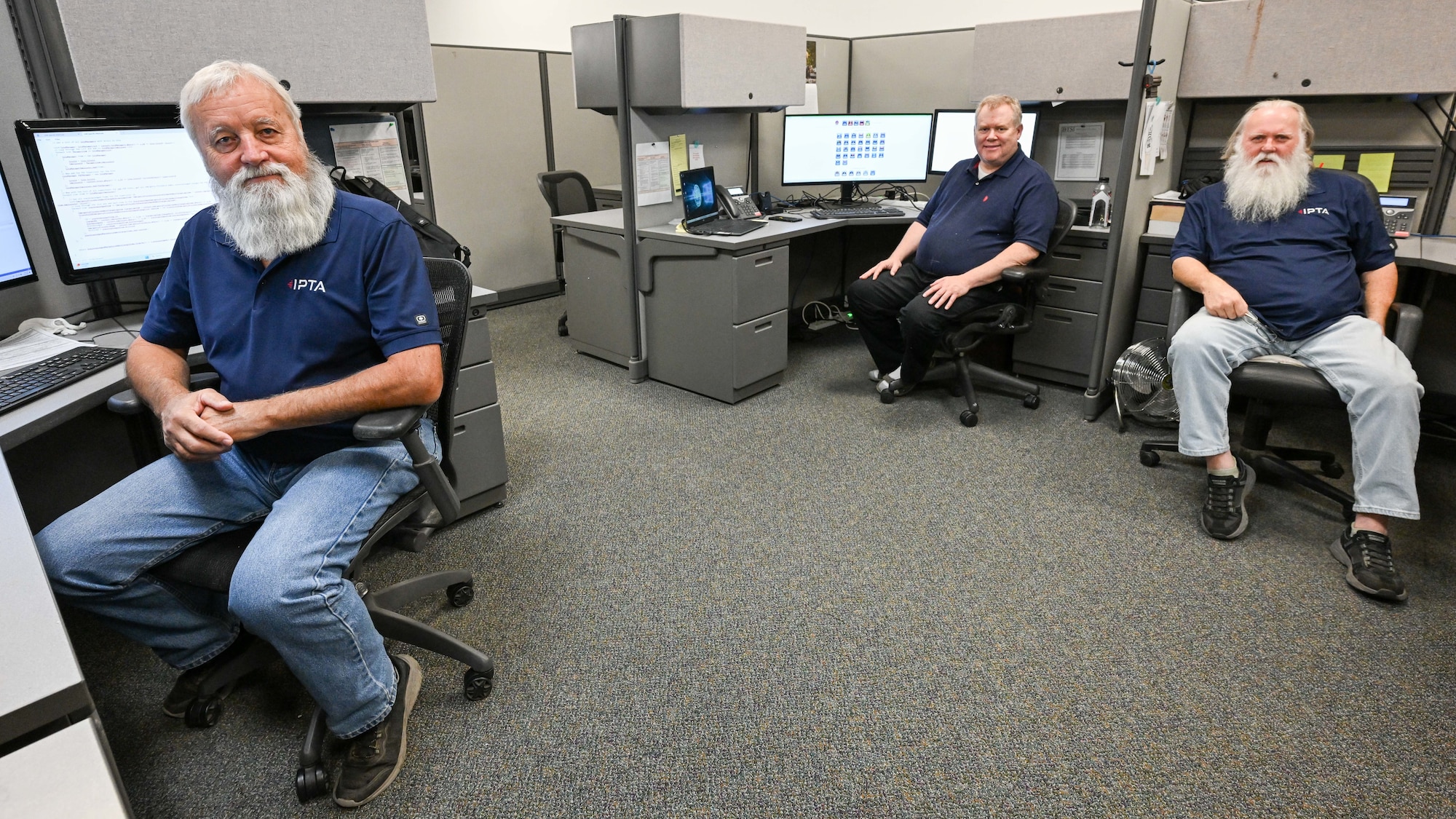 Three omputer technicians sit at computer workstations