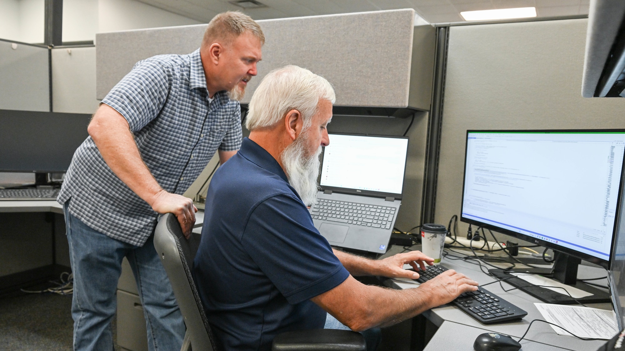 Three omputer technicians sit at computer workstations