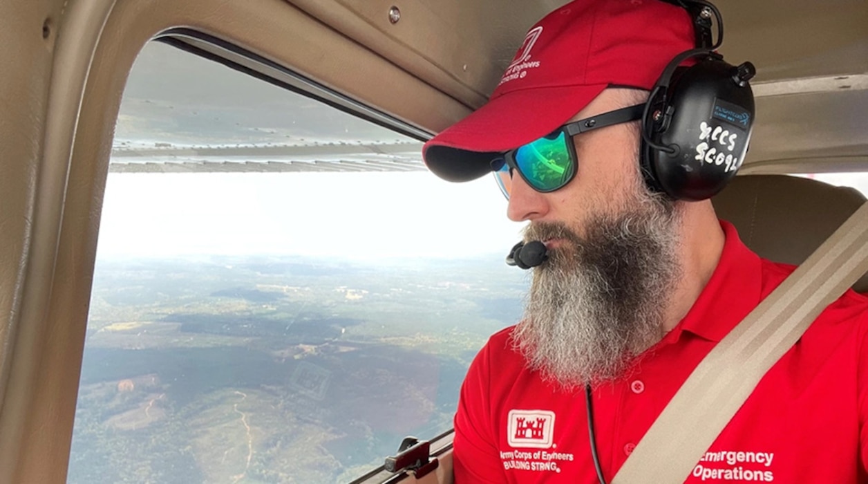 Man in a plane doing aerial assessment of hurricane damage.