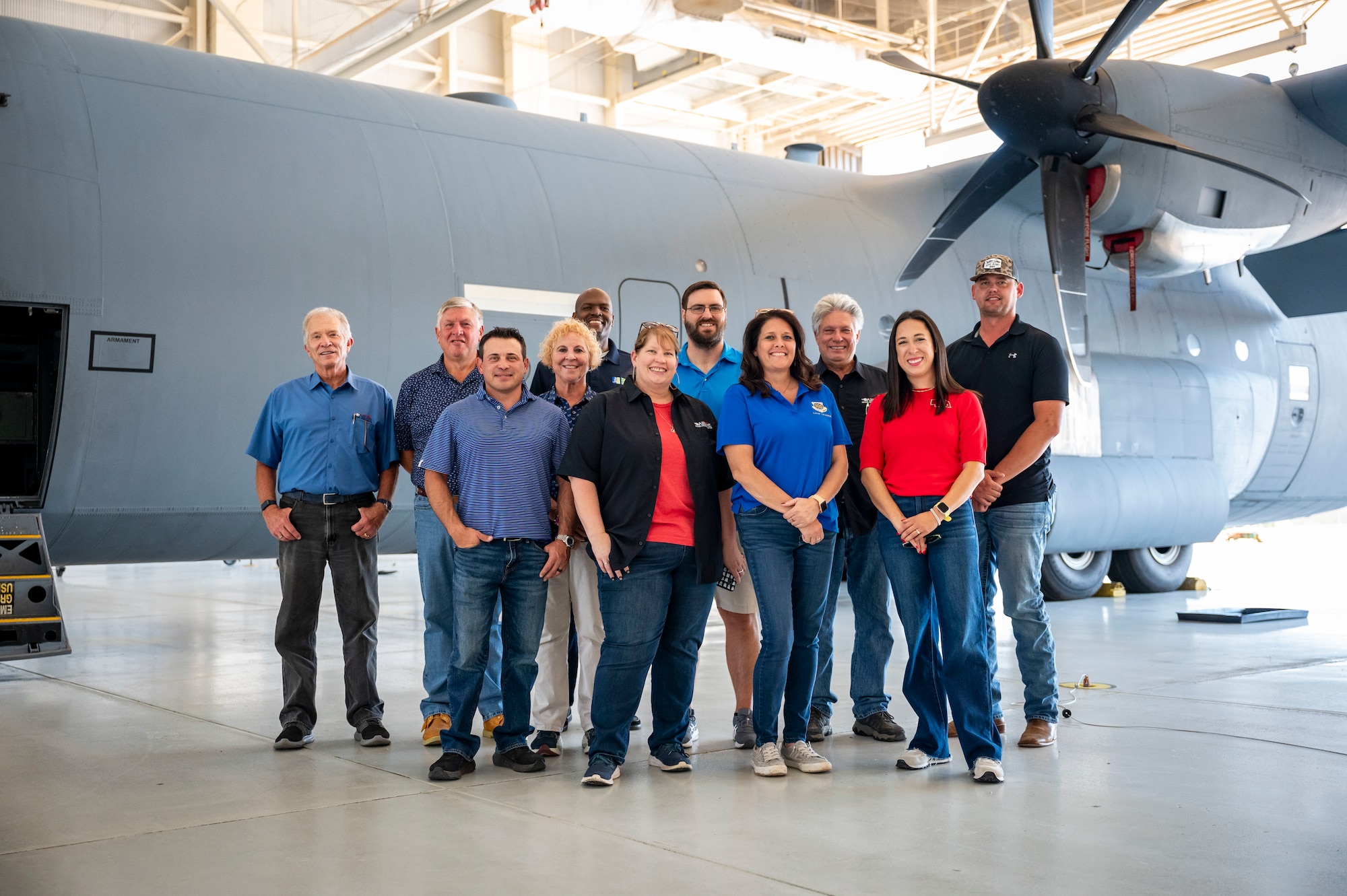 Honorary commanders pose for a group photo during a tour in front of a C-130J