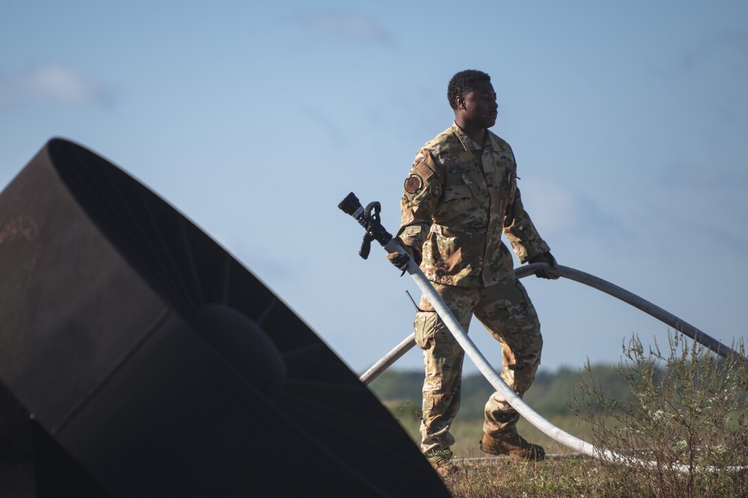 Airman carries fire hose