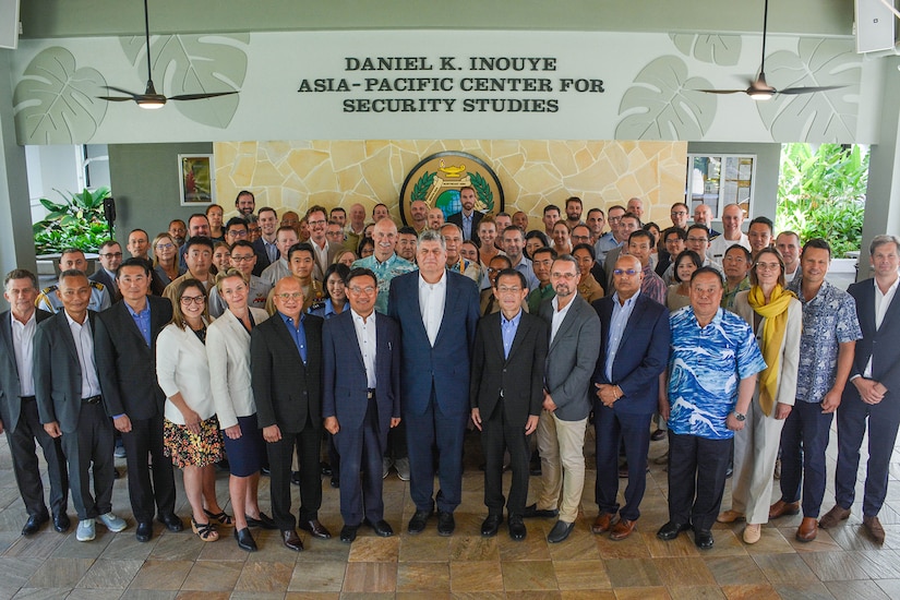 A group of people pose for a photo in front of signage that reads "Daniel K. Inouye Asia-Pacific Center for Security Studies."