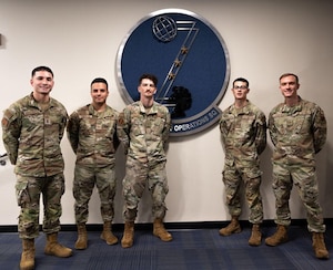 Airmen from the 83d Network Operations Squadron pose in front of the squadron logo.