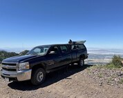 A shadowy figure of a member of the 2d Audiovisual Squadron is shown filming the Warriors Over the Wasatch Open House & Air Show from inside the bed of an enclosed pickup truck.