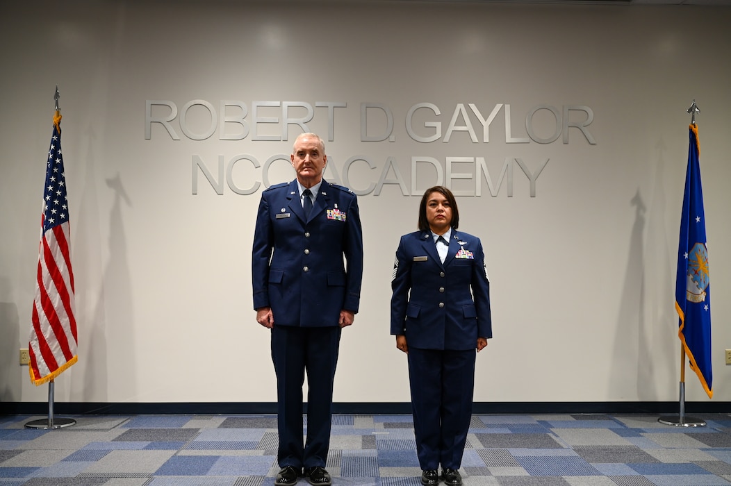 Chief Master Sgt. Lisa Lopez, 433rd Aeromedical Evacuation Squadron senior enlisted leader, and Retired Col. Michael D. Nelson, a former 433rd Medical Squadron commander, stands at attention during a retirement ceremony in Joint Base San Antonio-Lackland, Texas, Oct. 5, 2024.