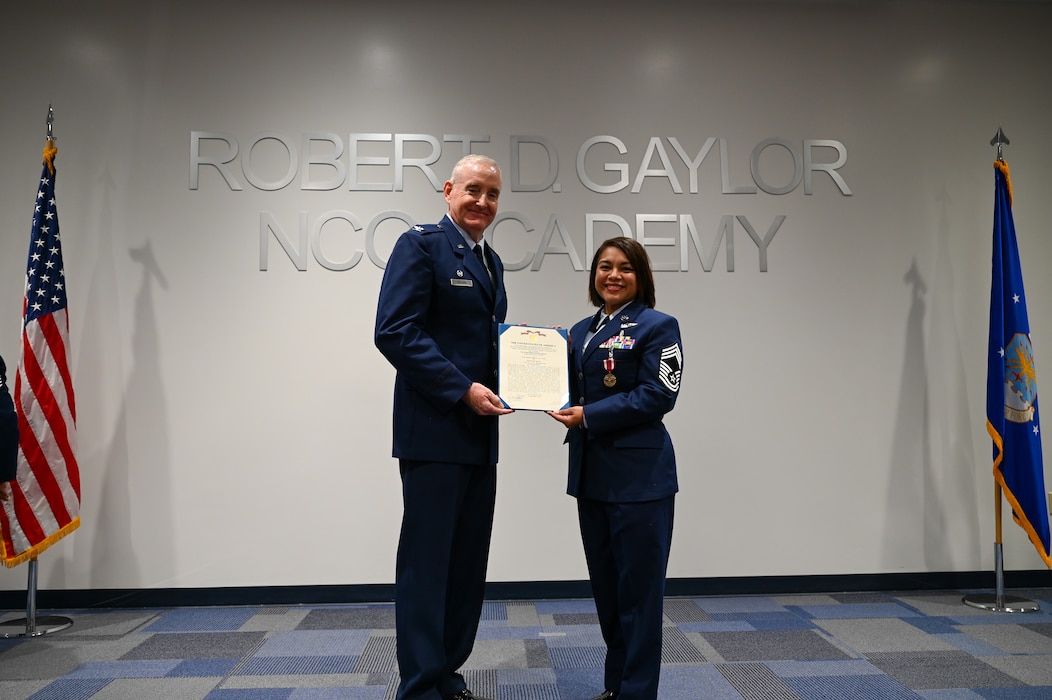 Retired Col. Michael D. Nelson, a former 433rd Medical Squadron commander, and Chief Master Sgt. Lisa Lopez, 433rd Aeromedical Evacuation Squadron senior enlisted leader, present the Meritorious Service Medal during a retirement ceremony for Lopez in Joint Base San Antonio-Lackland, Texas, Oct. 5, 2024.