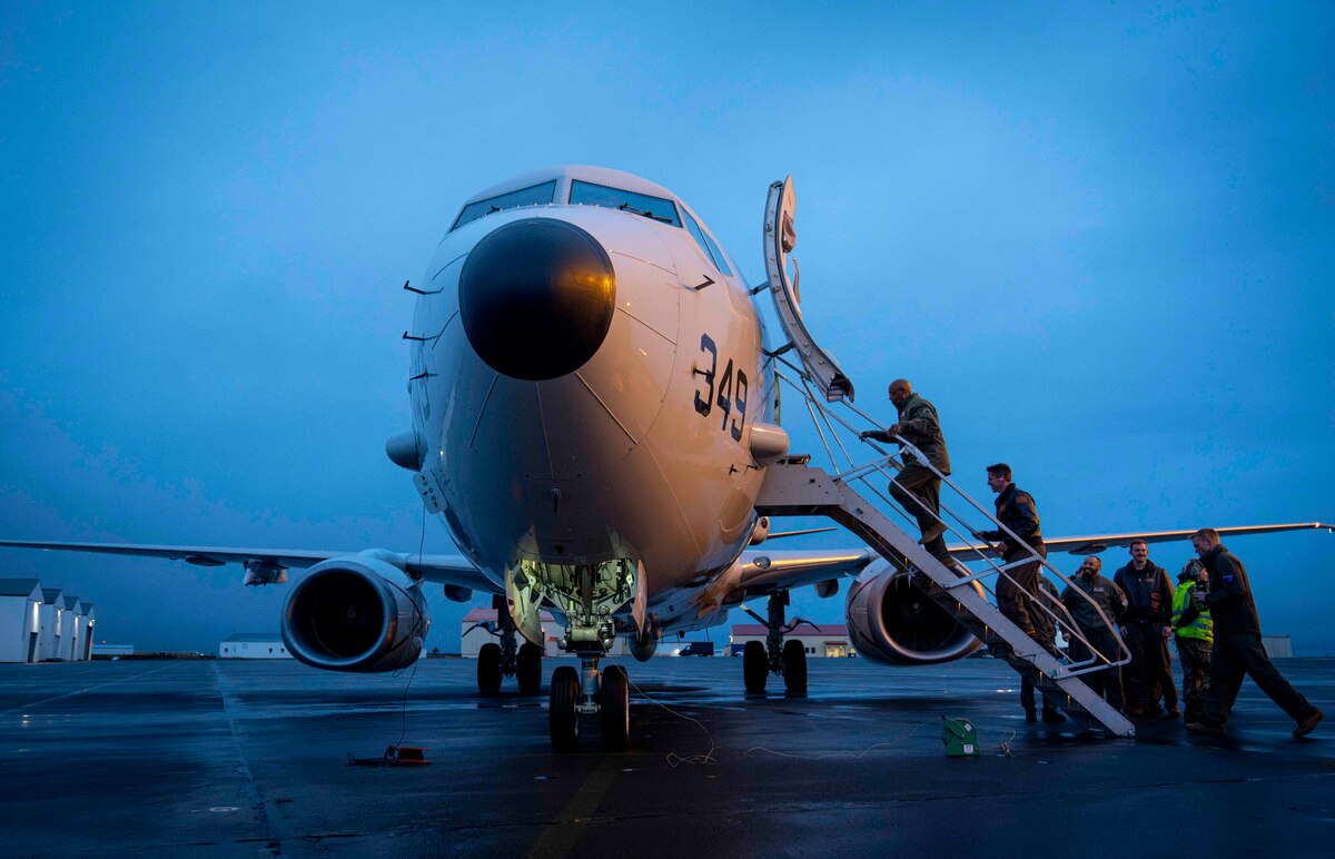 A service member in a flight suit boards a military plane.