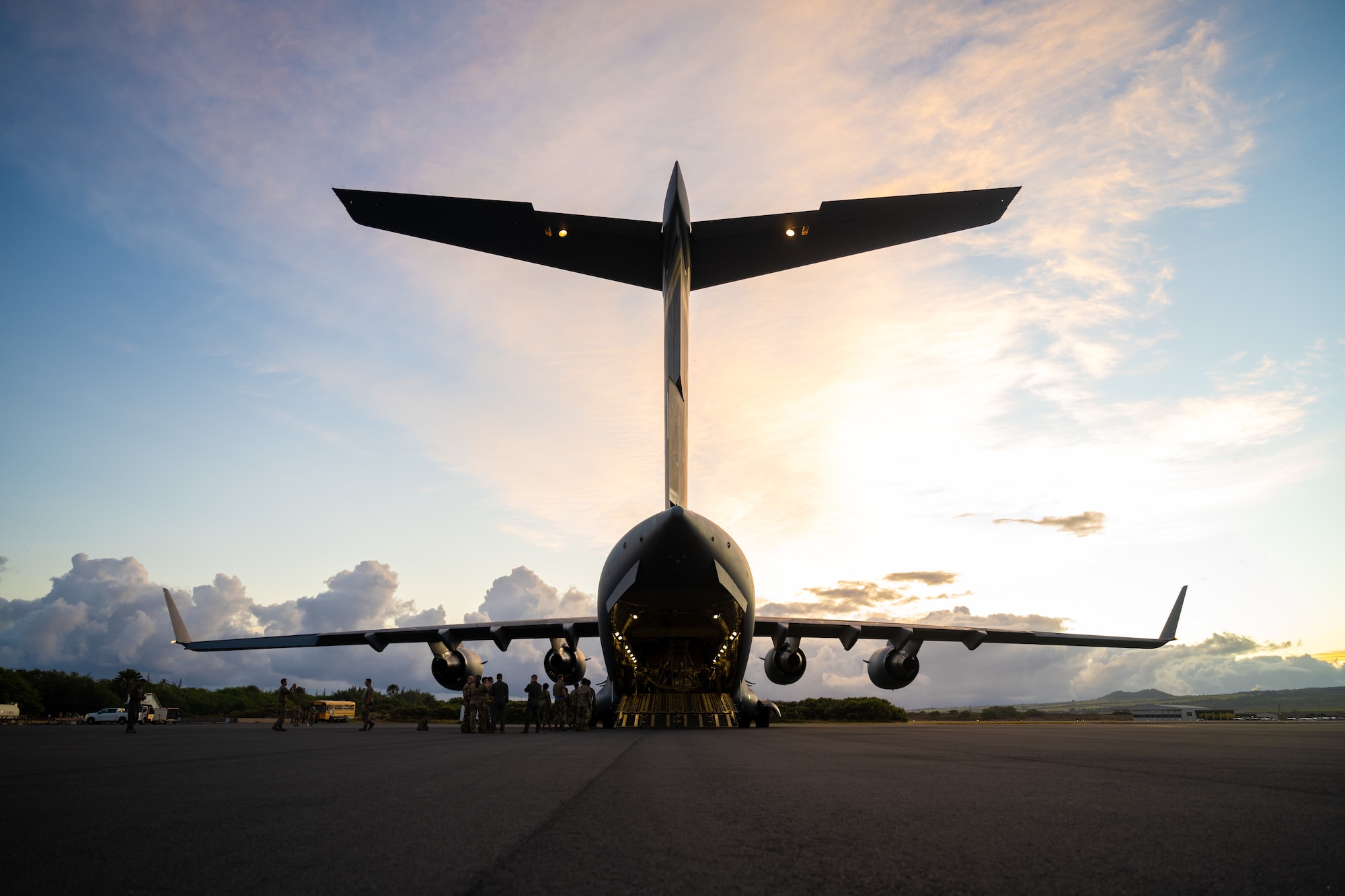 A U.S. Air Force C-17 Globemaster III aircraft is parked on a flightline during sunrise.