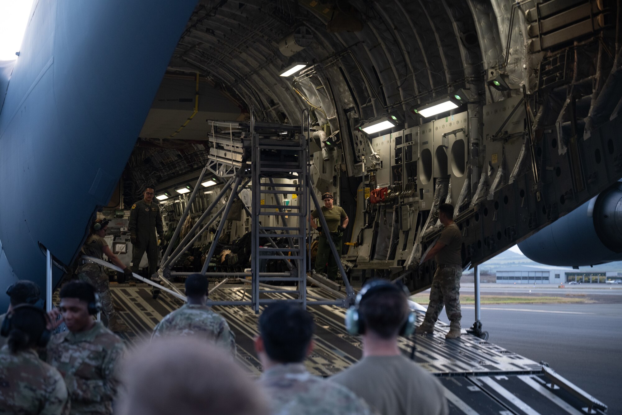 U.S. Air Force Airmen unload an aircraft stair ladder off a C-17 Globemaster III aircraft.