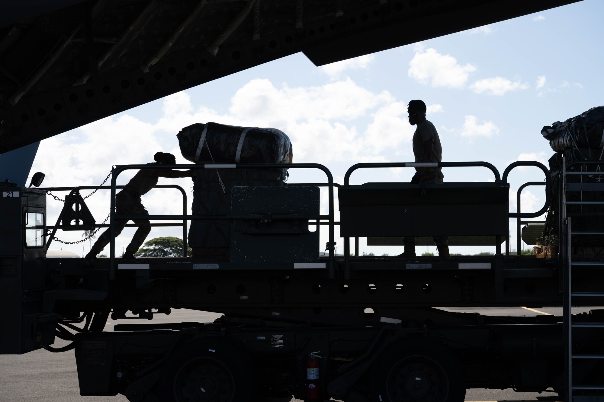 U.S. Air Force Airmen unload cargo from a C-17 Globemaster III for arriving U.S. Army Soldiers from the 11th Airborne Division on Joint Base Pearl Harbor-Hickam, Hawaii, Oct. 7, 2024 during Joint Pacific Multinational Readiness Center 25-01. The Joint Pacific Multinational Readiness Center (JPMRC) is the Army’s newest Combat Training Center (CTC) and generates readiness in the environments and conditions where our forces are most likely to operate in. JPMRC 25-01 includes training participants from across the U.S. Joint Force, and multinational Allies and partners. (U.S. Air Force photo by Airman 1st Class Aden Brown)