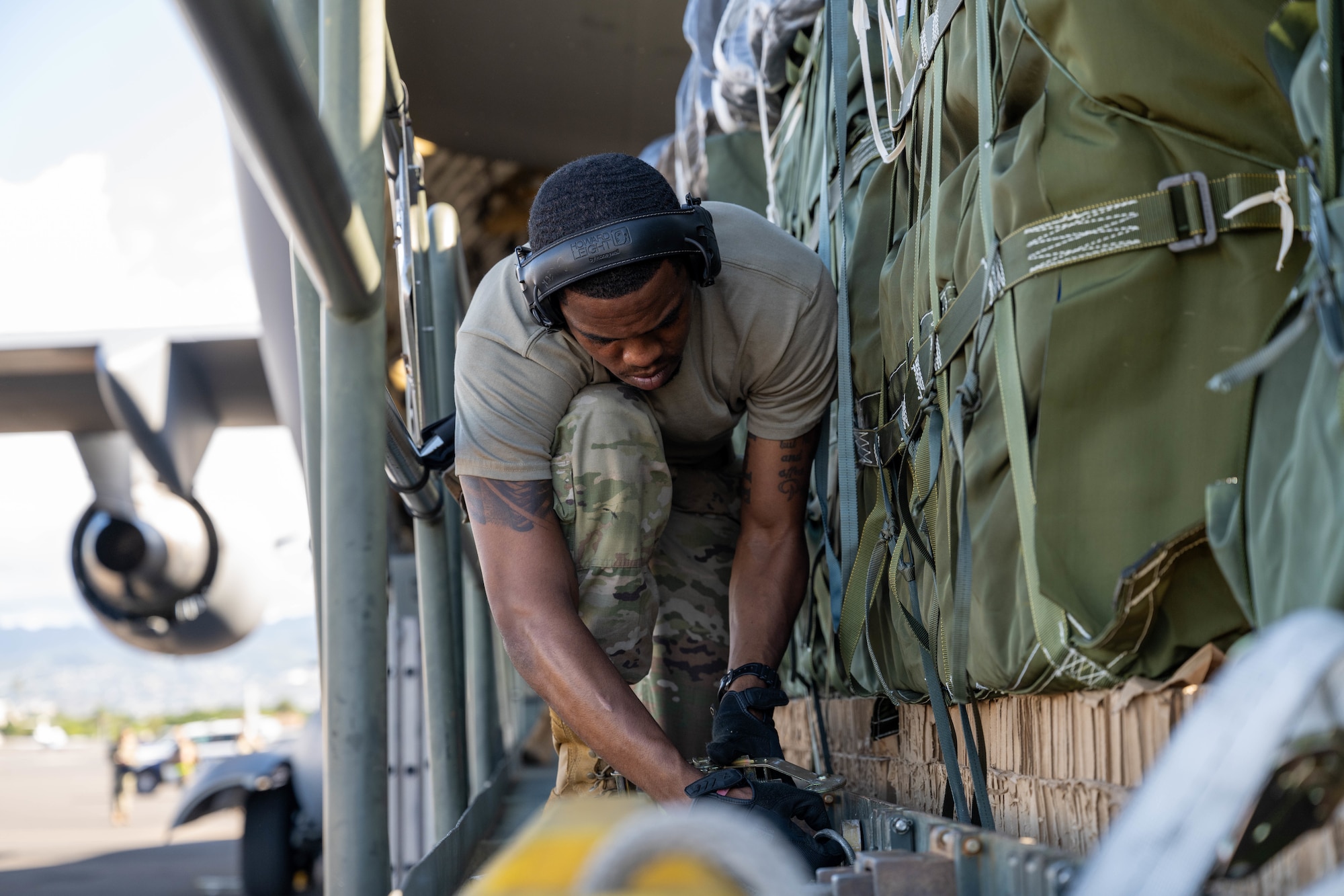 A U.S. Air Force Airman secures cargo to a K-loader on Joint Base Pearl Harbor-Hickam, Hawaii, Oct. 7, 2024 during Joint Pacific Multinational Readiness Center 25-01. The Joint Pacific Multinational Readiness Center (JPMRC) is the Army’s newest Combat Training Center (CTC) and generates readiness in the environments and conditions where our forces are most likely to operate in. JPMRC 25-01 includes training participants from across the U.S. Joint Force, and multinational Allies and partners. (U.S. Air Force photo by Airman 1st Class Aden Brown)