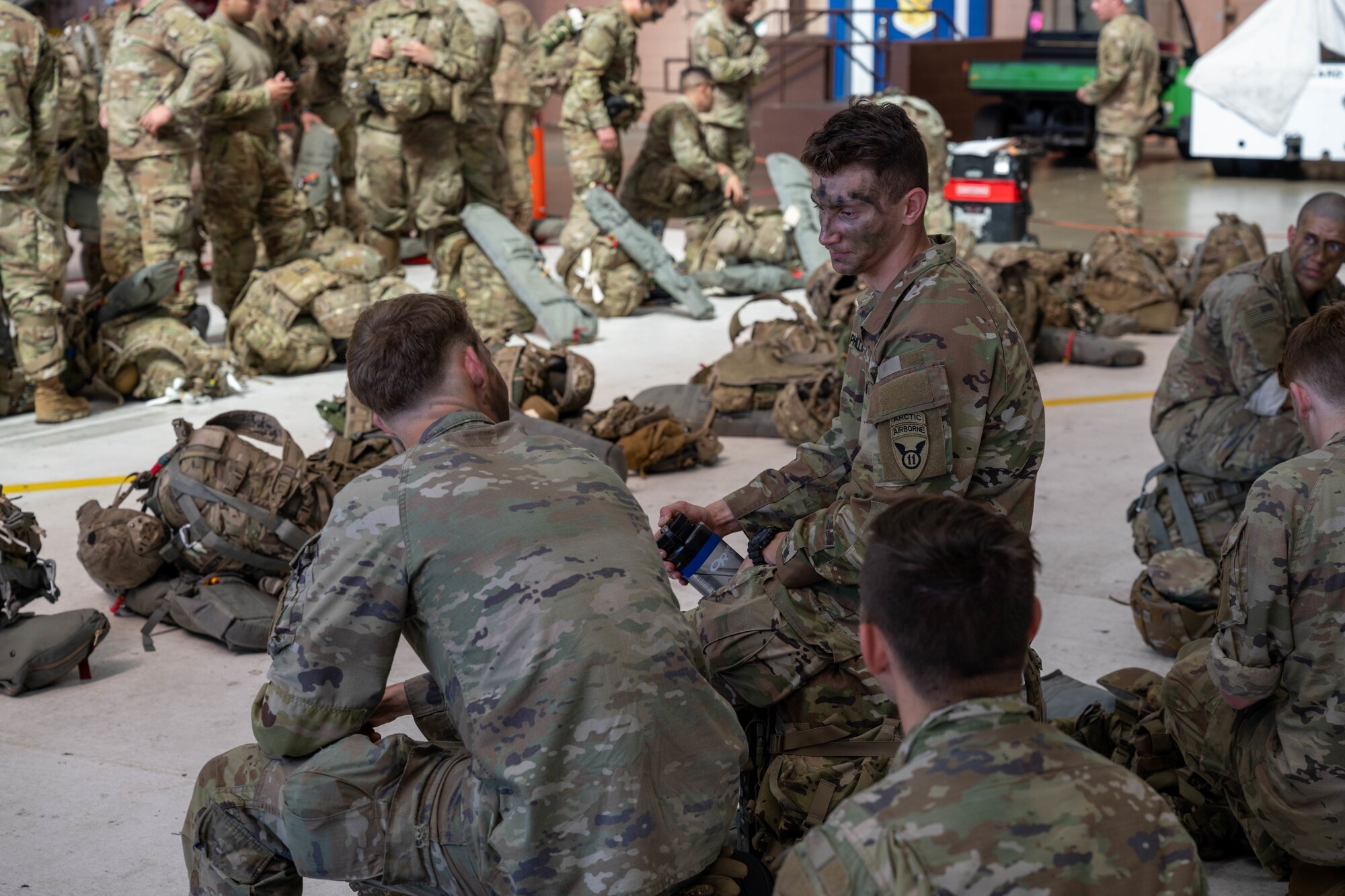 U.S. Army Soldiers with the 11th Airborne Division have a conversation in a hangar on Joint Base Pearl Harbor-Hickam, Hawaii, Oct. 7, 2024 during Joint Pacific Multinational Readiness Center 25-01. The Joint Pacific Multinational Readiness Center (JPMRC) is the Army’s newest Combat Training Center (CTC) and generates readiness in the environments and conditions where our forces are most likely to operate in. JPMRC 25-01 includes training participants from across the U.S. Joint Force, and multinational Allies and partners. (U.S. Air Force photo by Airman 1st Class Aden Brown)