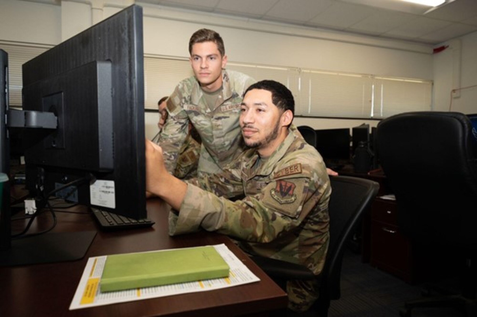 U.S. Air Force Airman 1st Class Austin Fackrell, 83d Network Operations Squadron directory services operator, left, assists U.S. Air Force Airman 1st Class Cristian Quintero, 83d NOS directory services operator, at Joint Base Langley-Eustis, Virginia, Oct. 8, 2024. Fackrell taught Quintero how to provide basic authentication for Airmen to access an online domain. (U.S. Air Force photo by Airman Donnell Ramsey)