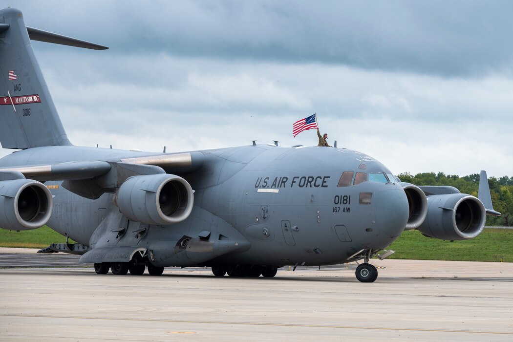 a person waves a flag out of the top of a cargo jet as it taxi's into parking