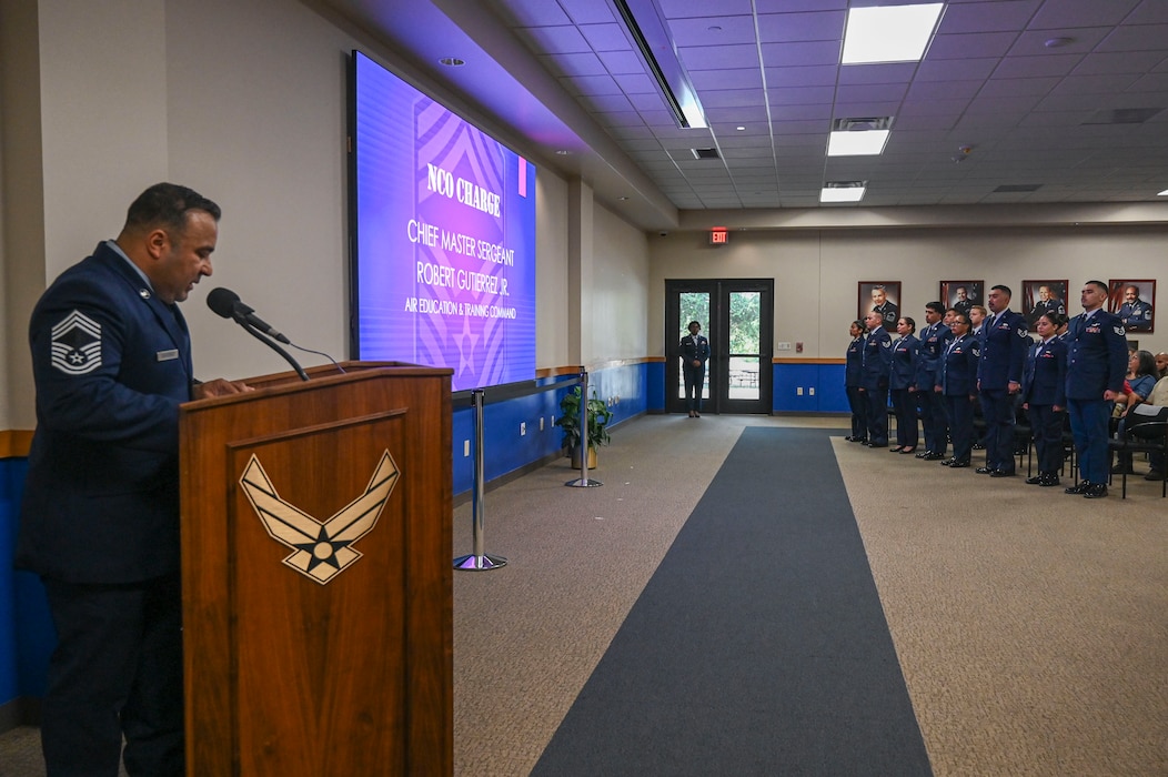 Chief Master Sgt. Robert Gutierrez Jr., center, Air Education and Training Command chief enlisted manager, delivers the Non-commissioned officer charge to the newly appointed NCOs of the 433rd Airlift Wing at the Pfingston Reception Center after the NCO Induction Ceremony on Joint Base San Antonio-Lackland, Texas on October 5, 2024.