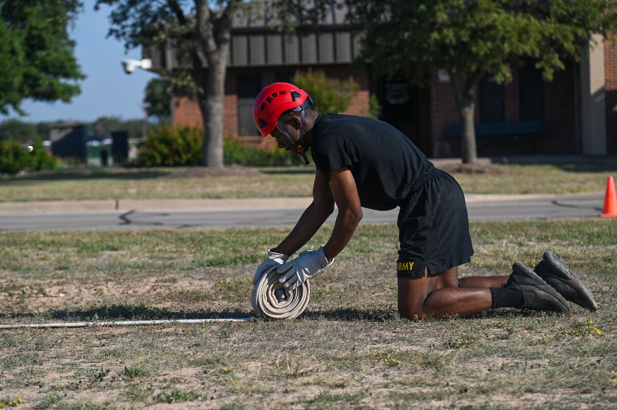 A U.S. Army soldier assigned to the 344th Intelligence Battalion rolls up a firehose as part of the Fire Muster event at Goodfellow Air Force Base, Texas, Oct. 11, 2024. Every year Goodfellow hosts events that endorse National Fire Prevention Week as it continues to serve as a powerful tool in raising awareness and promoting public safety. (U.S. Air Force photo by Airman 1st Class James Salellas)