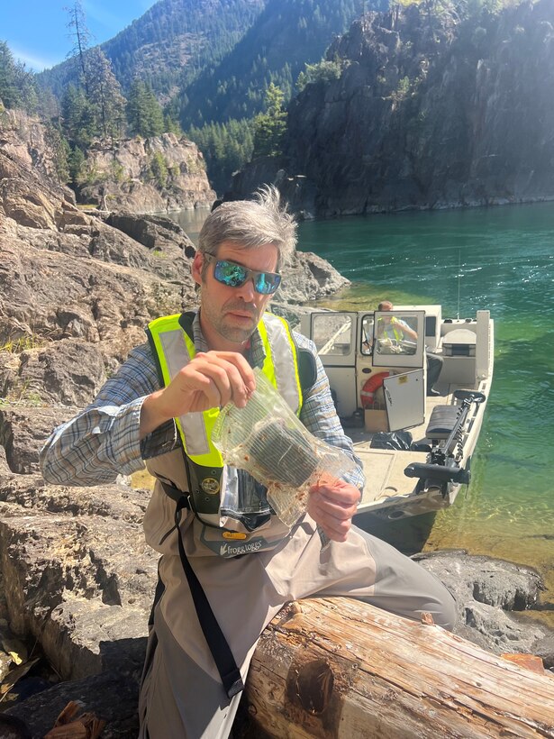 USACE Hydraulic Engineer Zac Corum checks a GPS unit placed in a log. Holes are drilled holes into the metal panel to help increase cellular connection.