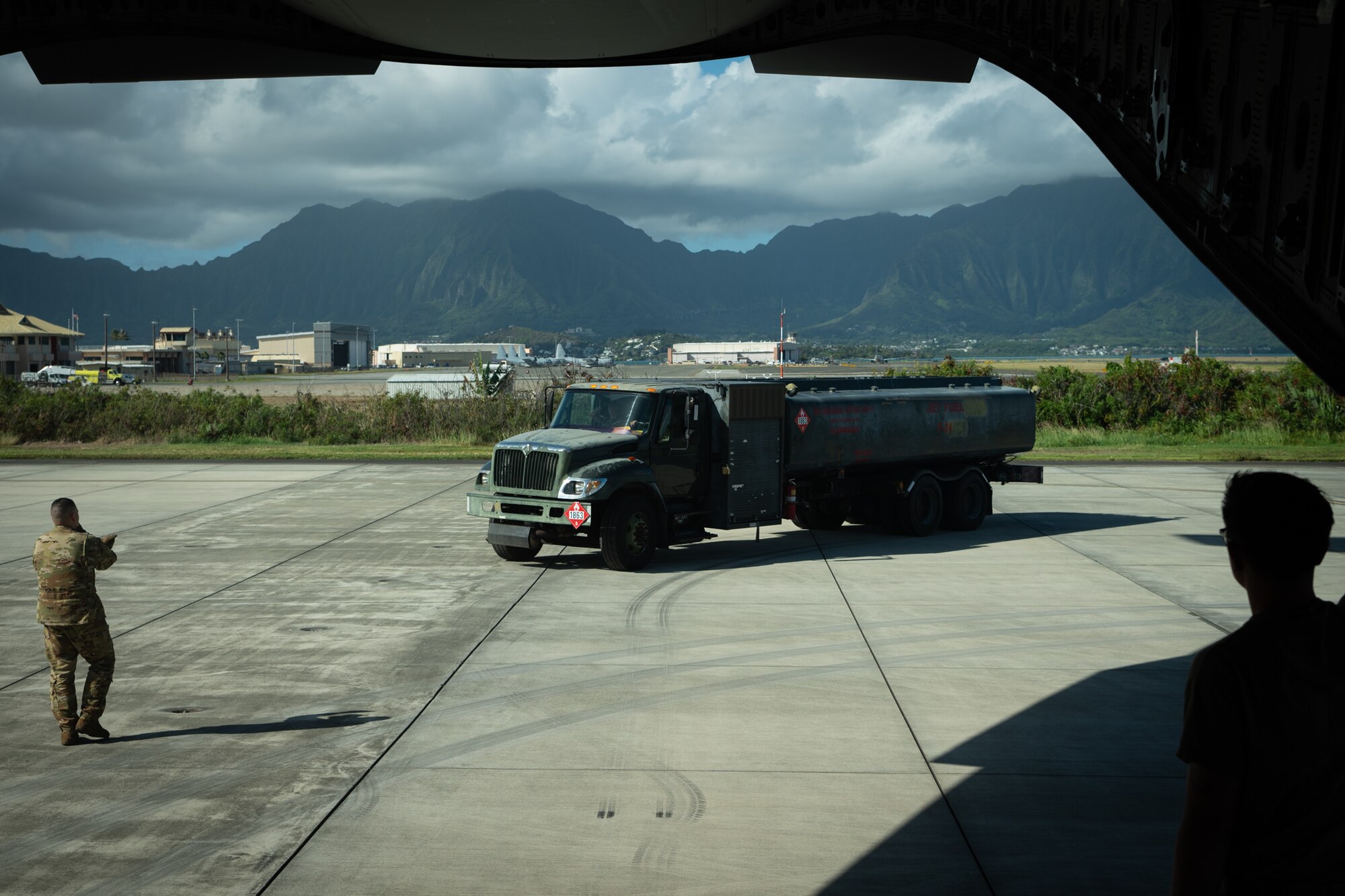 Senior Airman Nico Sharpe, a dedicated crew chief with the 7th Airlift Squadron, marshals a 62d Logistics Readiness Squadron Petroleum, Oils, and Lubricants truck onto a C-17 Globemaster III at Kōnelohe Marine Base in support of Exercise Rainier War 25A, Oct. 9, 2024.