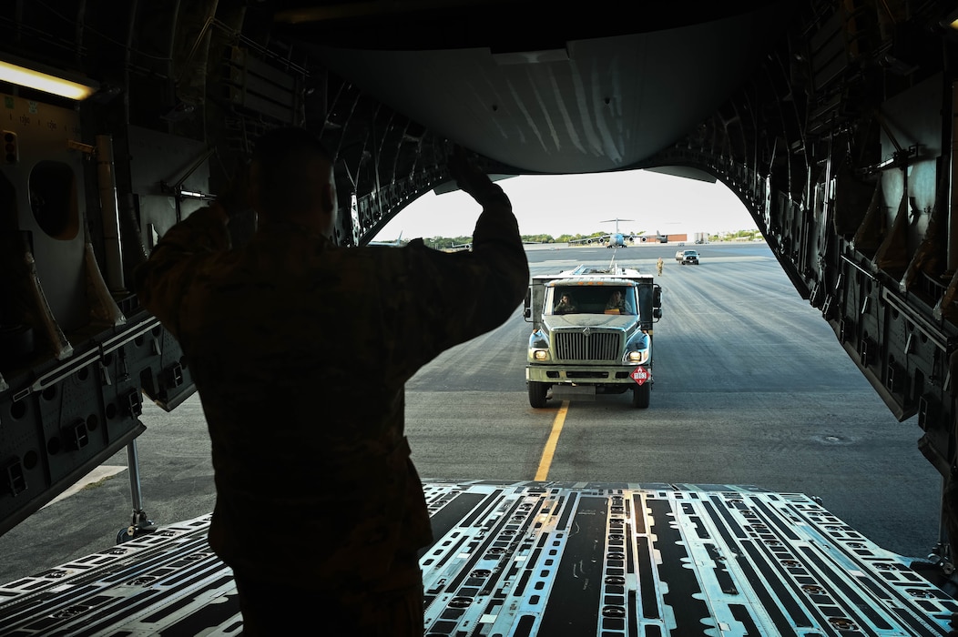 Senior Airman Nico Sharpe, a 7th Airlift Squadron dedicated crew chief, marshals a 62d Logistics Readiness Squadron Petroleum, Oils, and Lubricants truck onto a C-17 Globemaster III in support of Exercise Rainier War 25A, Oct. 9, 2024.