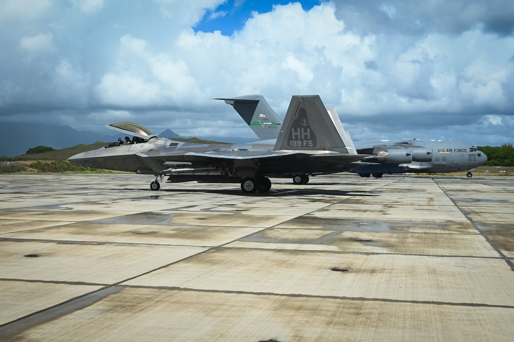 A U.S. Air Force C-17 Globemaster III from Joint Base Lewis-McChord and F-22 Raptors from Hickam Air Force Base sit on the flight line at Marine Corps Base Hawaii during Exercise Rainier War 25A, Oct. 9, 2024.