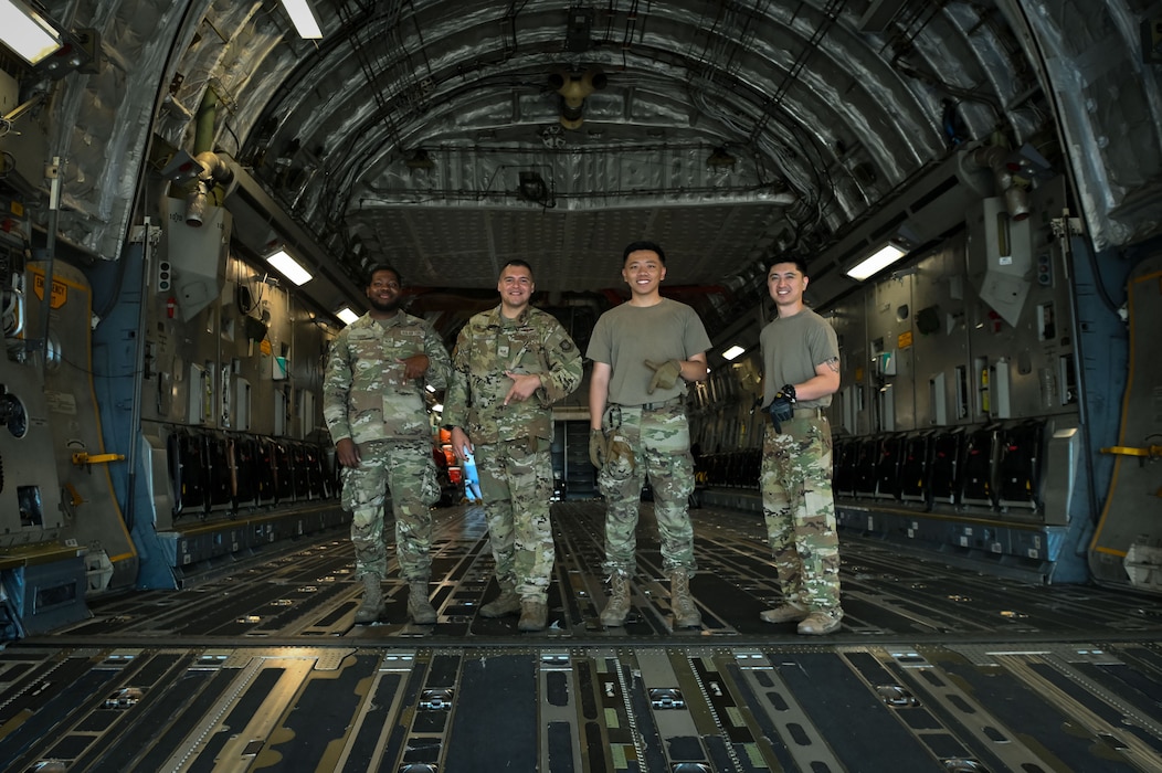 Aircrew members from the 7th Airlift Squadron pose in the cargo hold of a C-17 Globemaster III, shaping their fingers into the number seven to represent their squadron, Oct. 9, 2024, during Exercise Rainier War 25A.