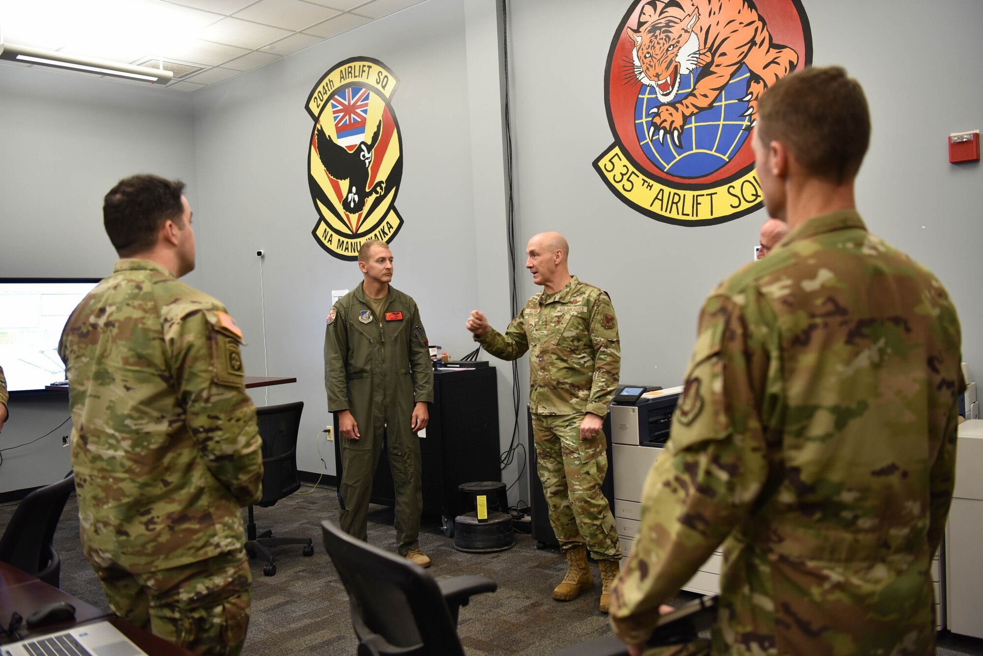 Air Force Chief of Staff Gen. David Allvin talks in a room with several other Airmen.