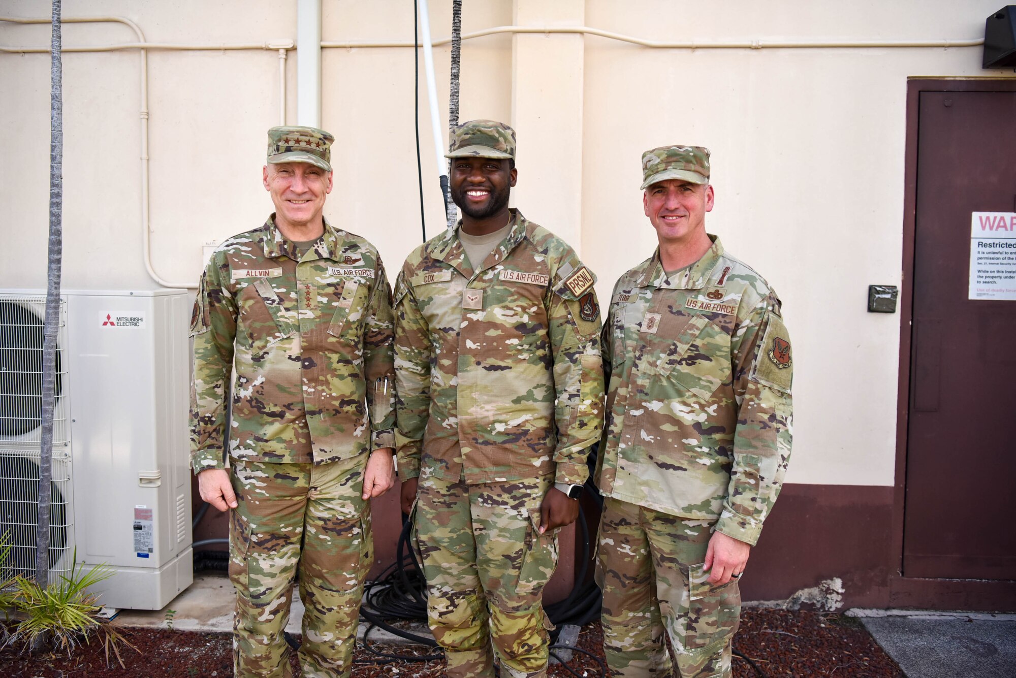 Air Force Chief of Staff Gen. David Allvin and Chief Master Sgt. of the Air Force David Flosi stand together for a group photo with an Airman.