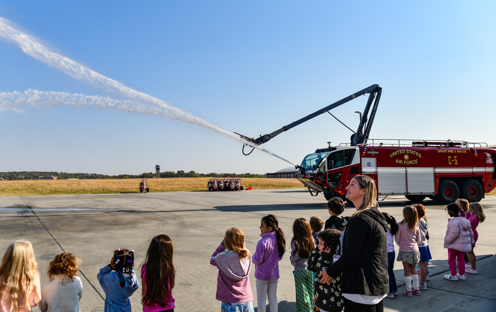 Kindergarten students from Birchcrest Elementary watch a fire engine spray water during a tour of Offutt Air Force Base's fire department during National Fire Prevention Week on Oct. 10, 2024. The theme of this year's National Fire Prevention Week was "Smoke Alarms: Make Them Work for You." (U.S. Air Force photo by Chad Watkins)