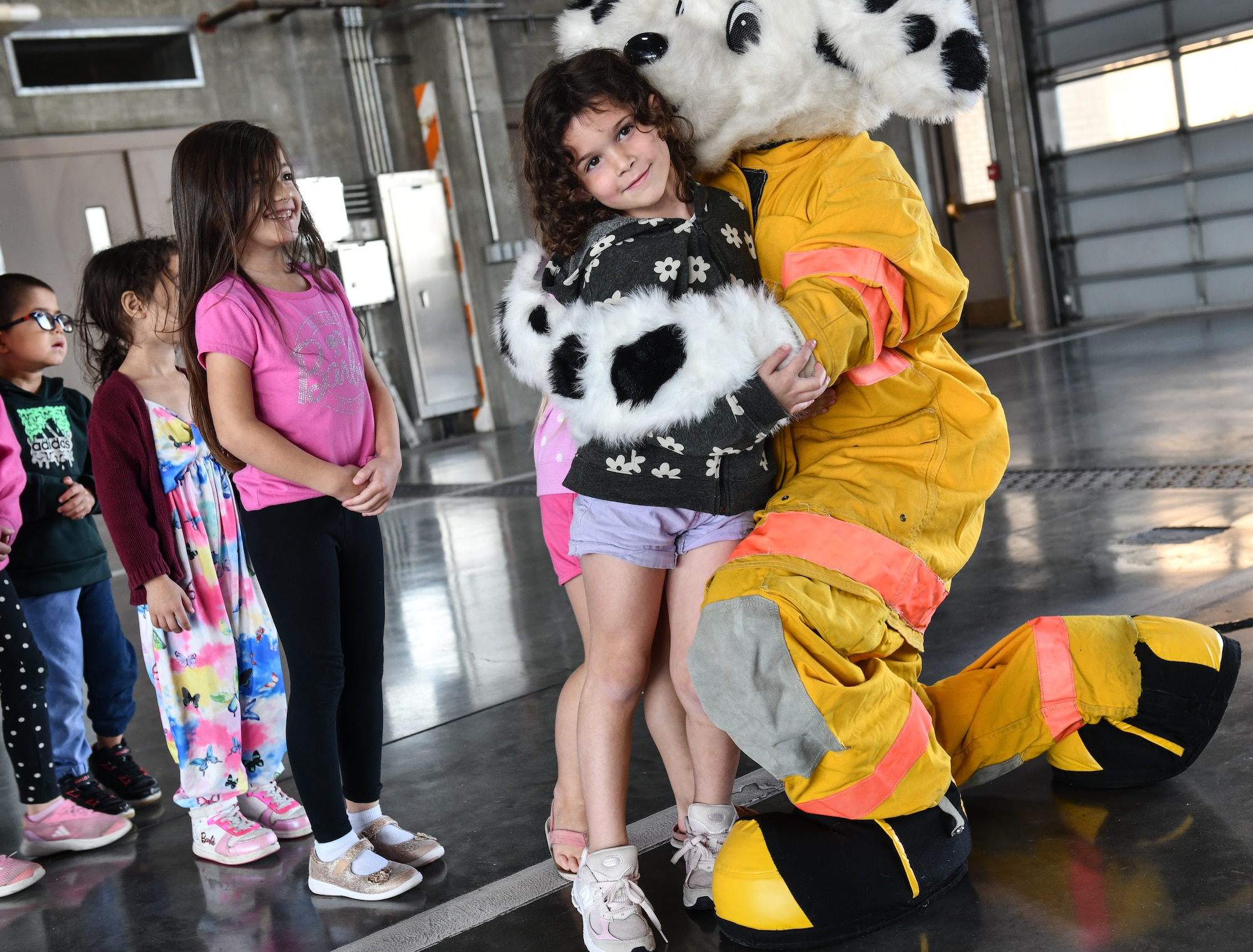 Adeline, a kindergarten student from Birchcrest Elementary, gets a hug from Sparky the Fire Dog during a tour of Offutt Air Force Base's fire department for National Fire Prevention Week on Oct. 10, 2024. The theme of this year's National Fire Prevention Week was "Smoke Alarms: Make Them Work for You." (U.S. Air Force photo by Chad Watkins)