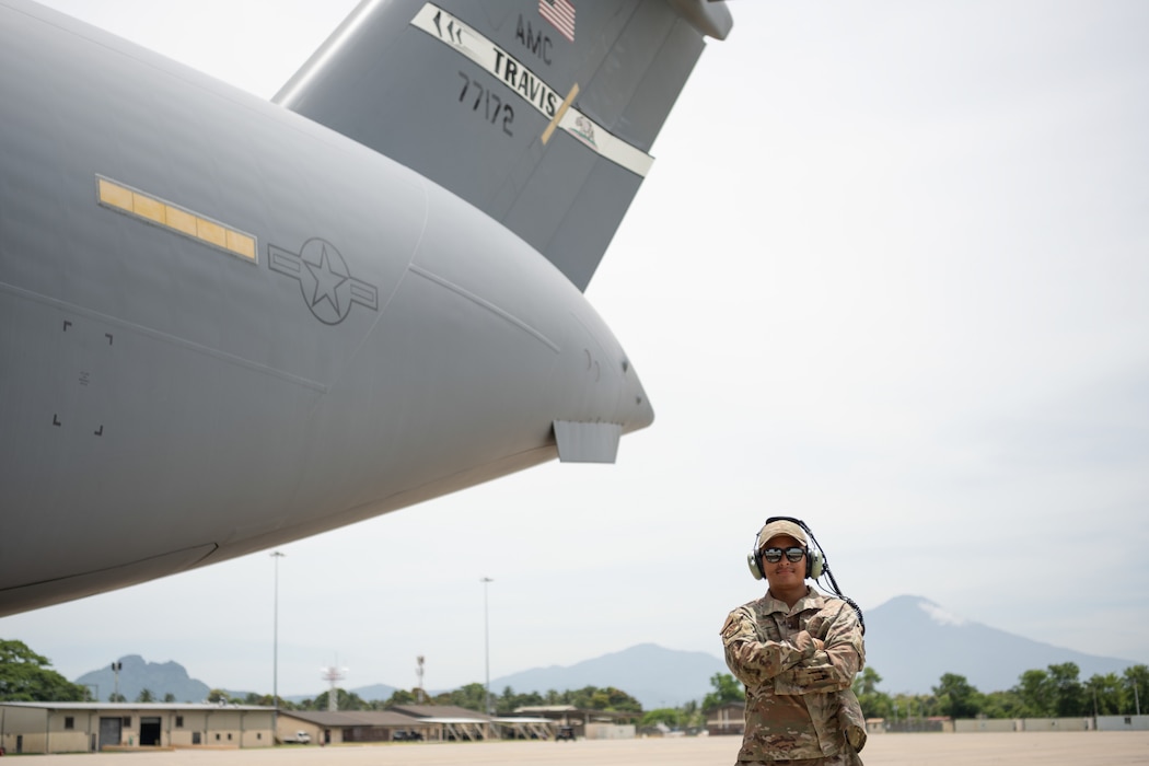 an airman standing besides a military aircraft