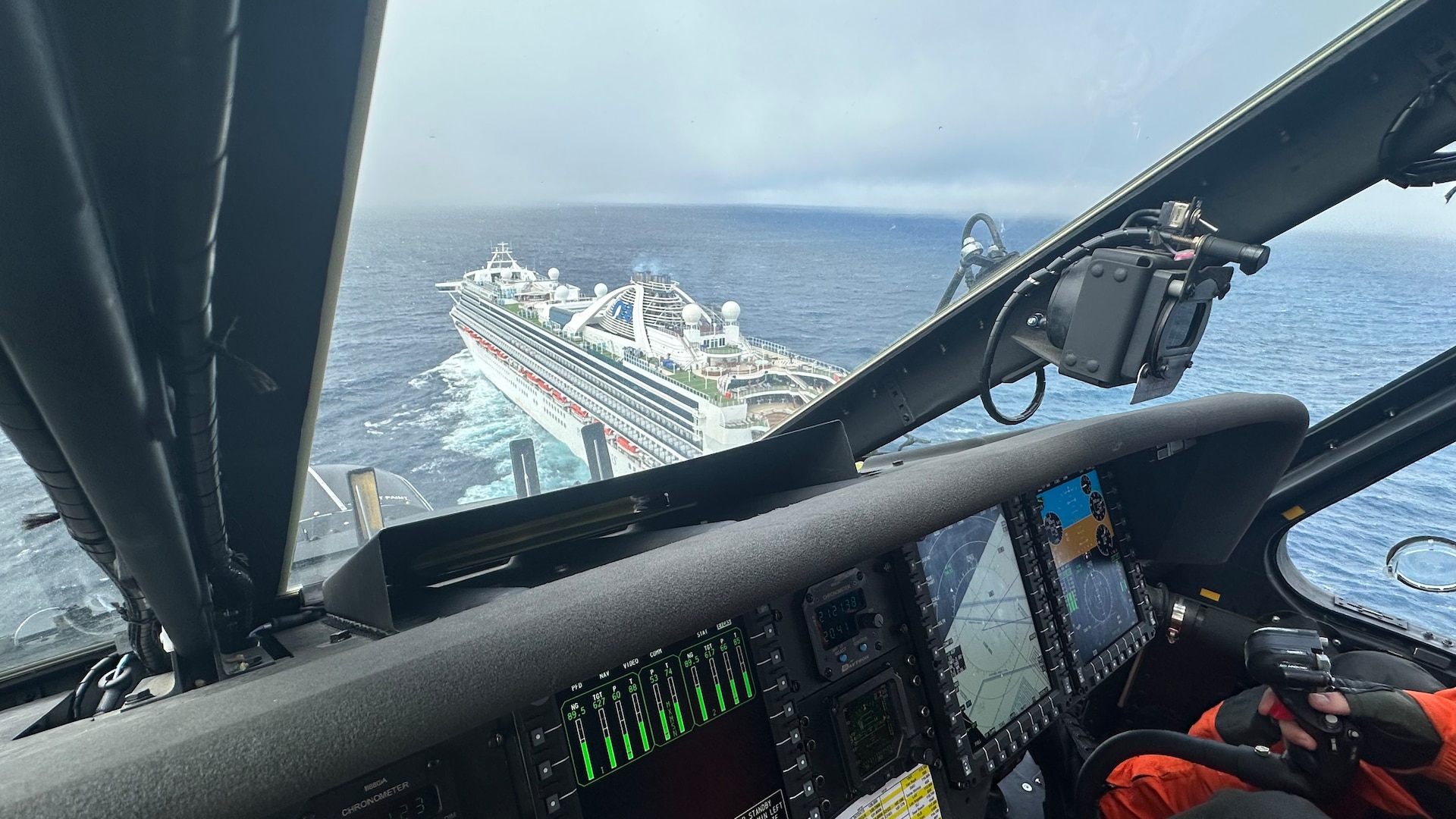 A cruise ship is seen from the cockpit of a helicopter.