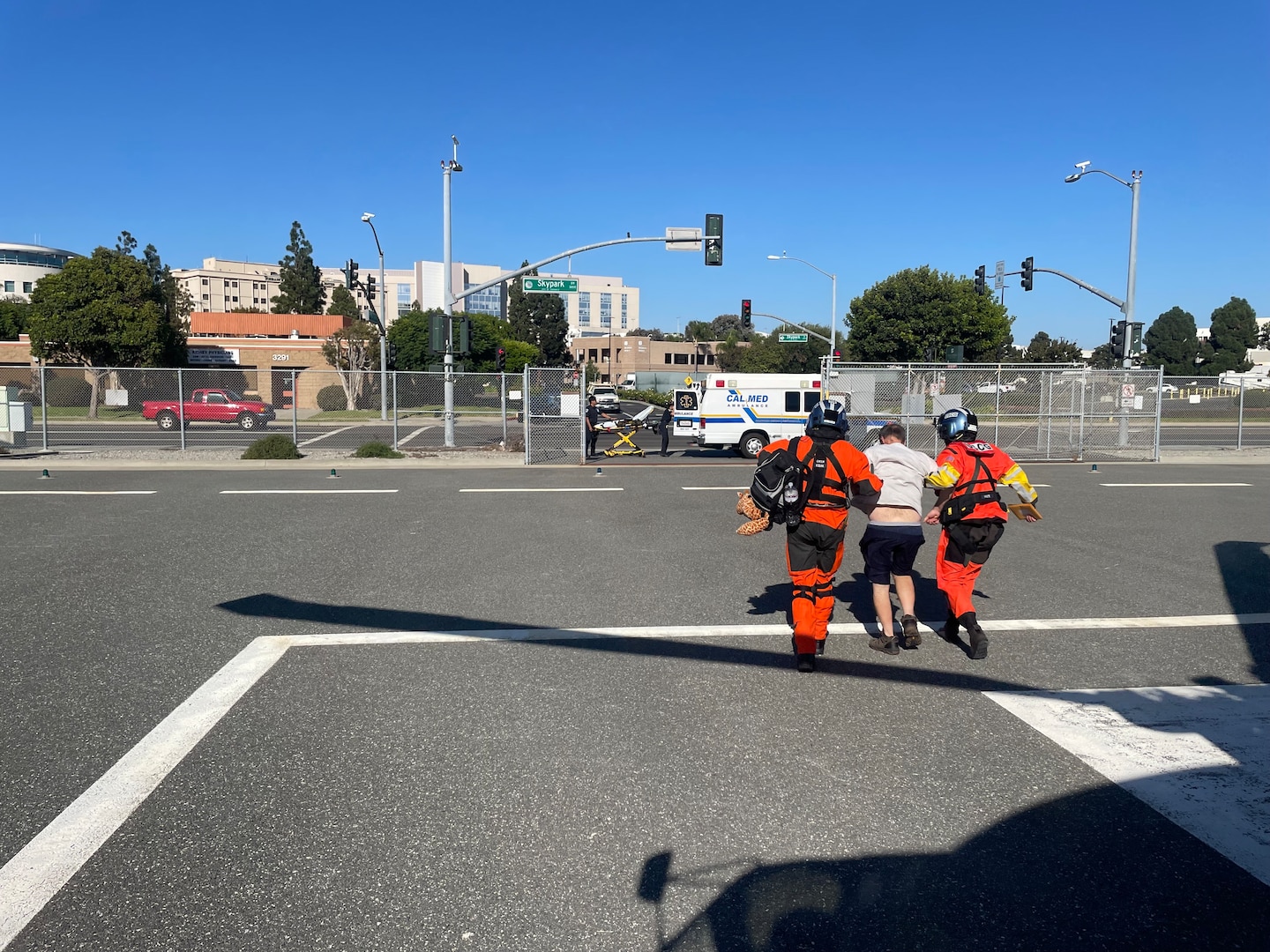 Two Coast Guardsmen escort a man to an awaiting ambulance.