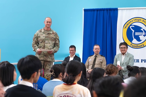 U.S. Air Force Col. Richard McElhaney stands with certificate in his hands to award the students for their work.