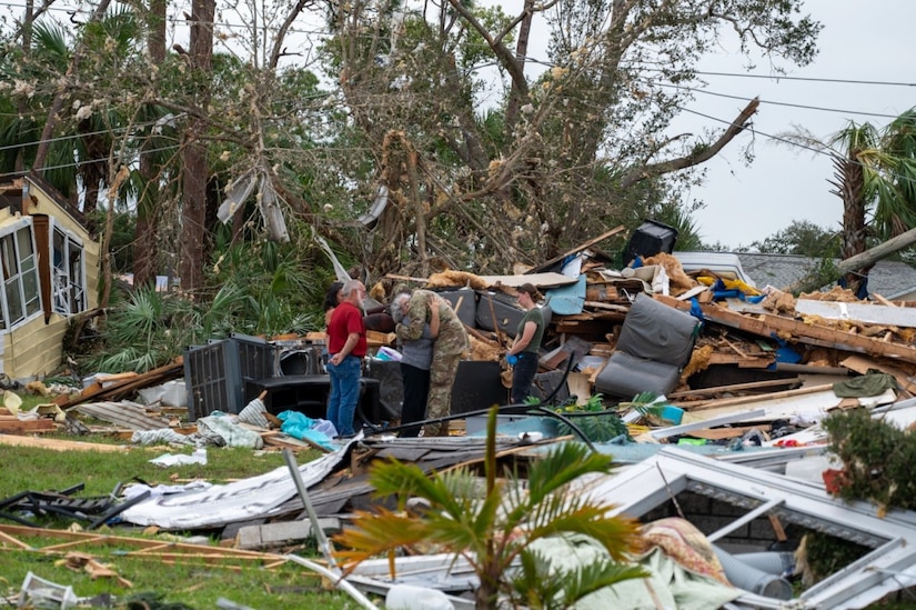 A soldier hugs a civilian among debris.