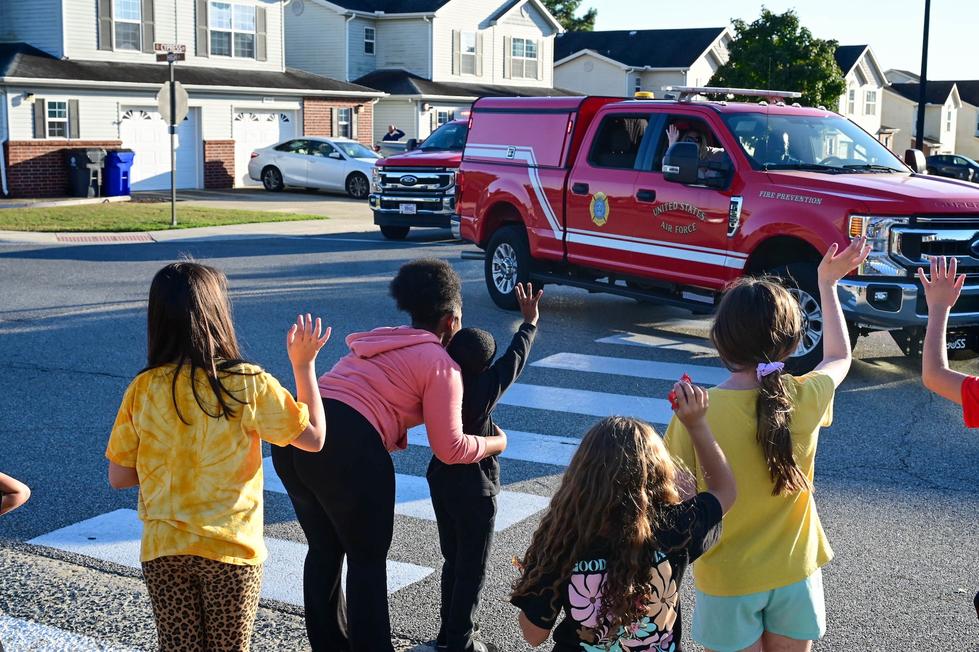 Base housing residents wave at firetrucks and first responder vehicles belonging to the 436th Civil Engineer Squadron during the 2024 Fire Prevention Week Parade at Dover Air Force Base, Delaware, Oct. 11, 2024. During Fire Prevention Week, the Dover AFB Fire Department hosted various activities to raise fire safety awareness for Airmen and their families. (U.S. Air Force photo by Mauricio Campino)
