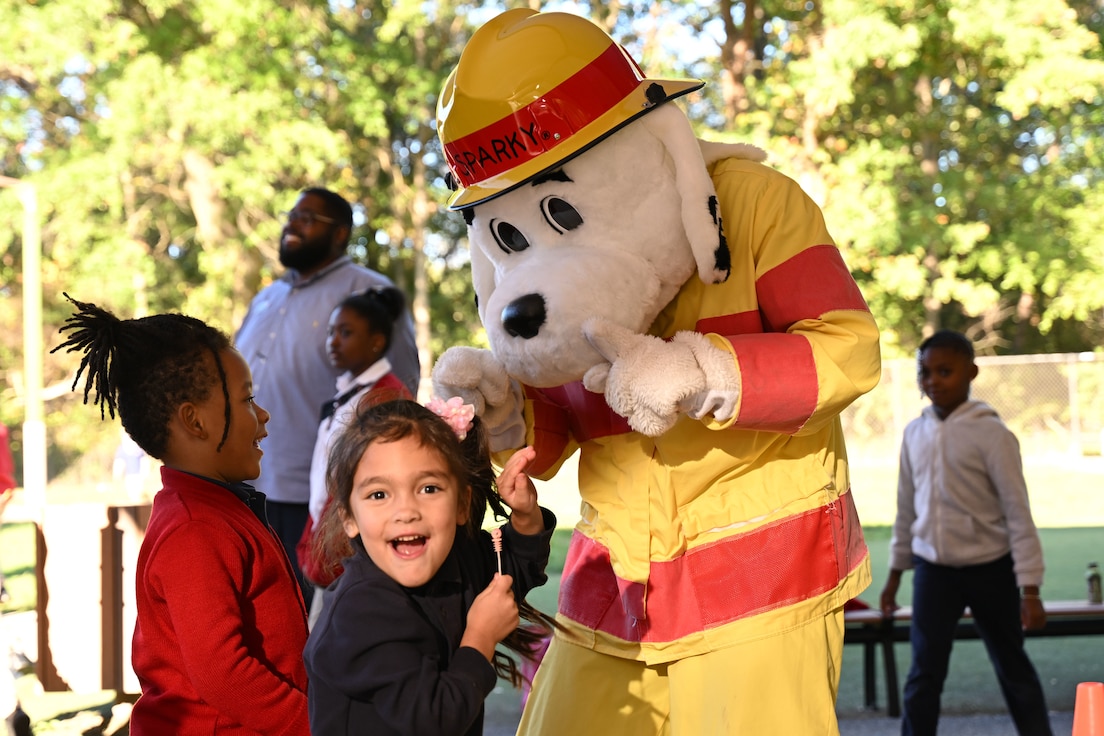 Sparky the Fire Dog bids farewell to children at the close of the Mini Muster fire safety event at Joint Base Andrews, Md., Oct. 10, 2024. The event, part of Fire Prevention Week, featured a circuit-style race ensuring children were exposed to firefighting tools and techniques, contributing to a safer JB Andrews community. (U.S. Air Force photo by Airman 1st Class Gianluca Ciccopiedi)