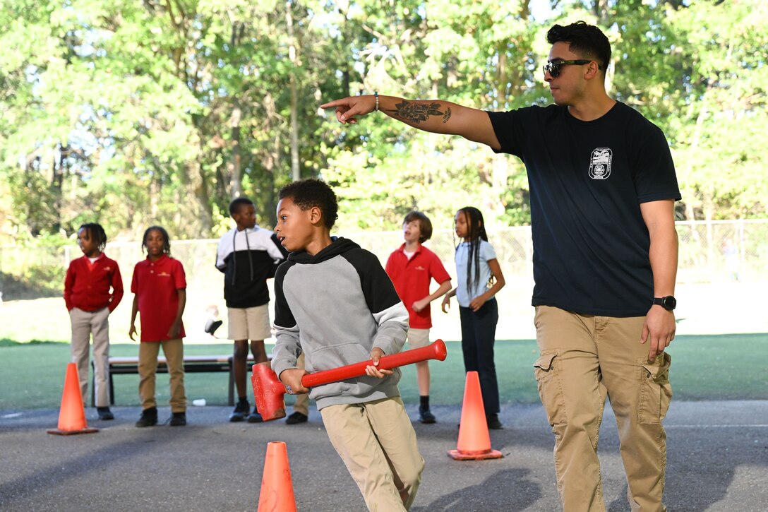 Matthew Arguijo, a firefighter assigned to the 316th Civil Engineer Squadron, helps a child navigate a circuit-style race during the Mini Muster fire safety event at Joint Base Andrews, Md., Oct. 10, 2024. The event was part of the base’s Fire Prevention Week activities to promote fire safety and risk reduction. (U.S. Air Force photo by Airman 1st Class Gianluca Ciccopiedi)