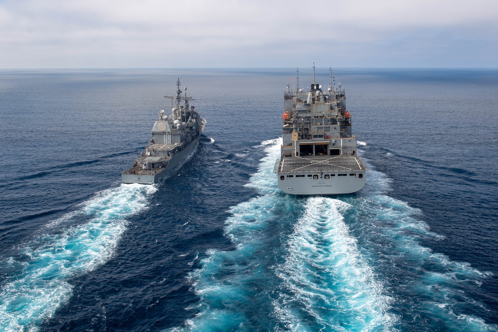 The Ticonderoga-class guided-missile cruiser USS Chosin (CG 65) steams alongside the Lewis and Clark-class dry cargo ship USNS Washington Chambers (T-AKE 11) during an at-sea demonstration of the Transferrable Reload At-sea Method (TRAM) while underway in the Pacific Ocean Oct. 11, 2024. Sailors aboard Chosin used the hydraulically- powered TRAM device to load an empty missile canister into the ship’s MK 41 Vertical Launching System (VLS) while off the coast of San Diego.